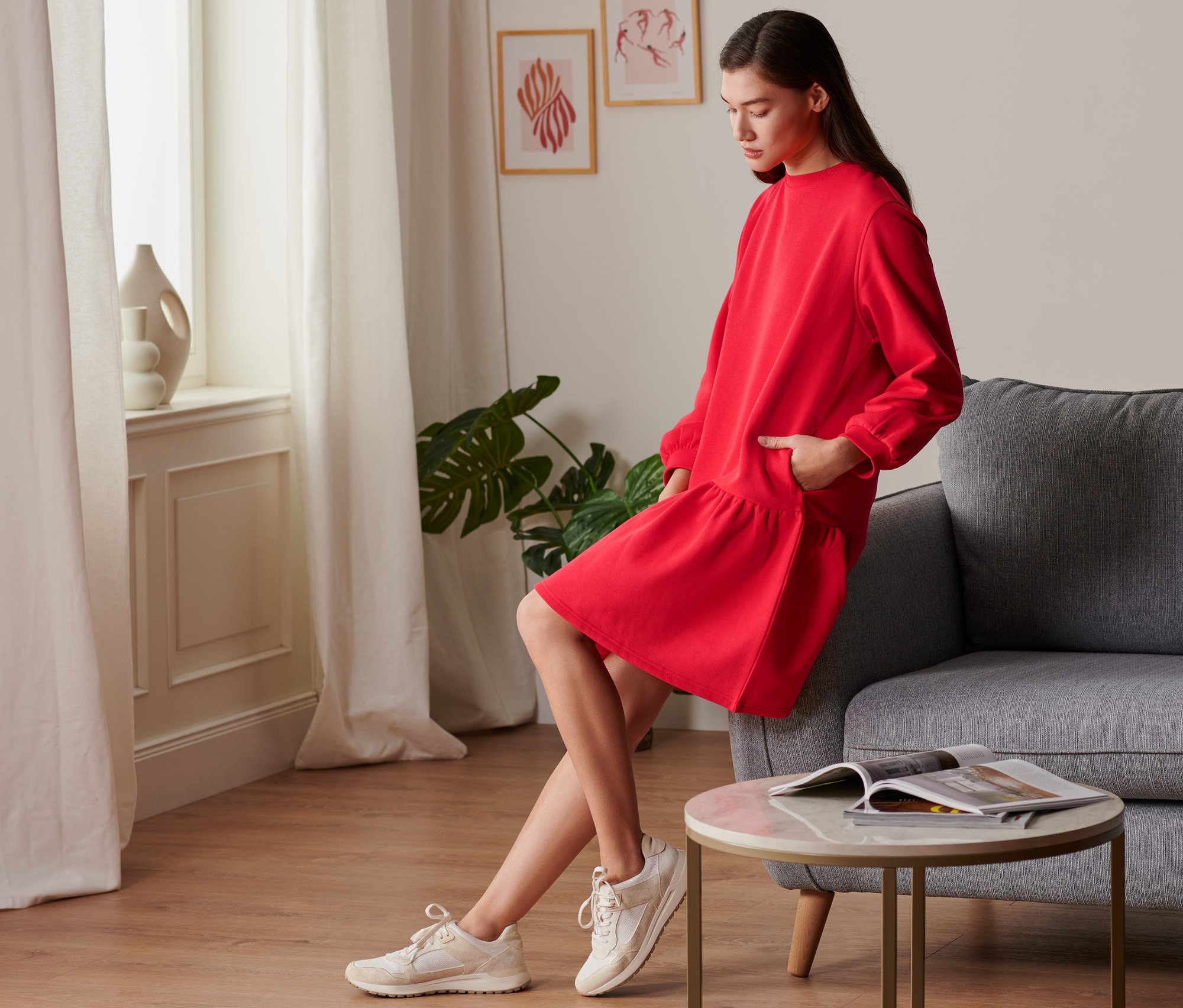 Nő pózol piros szabadidőruhában.