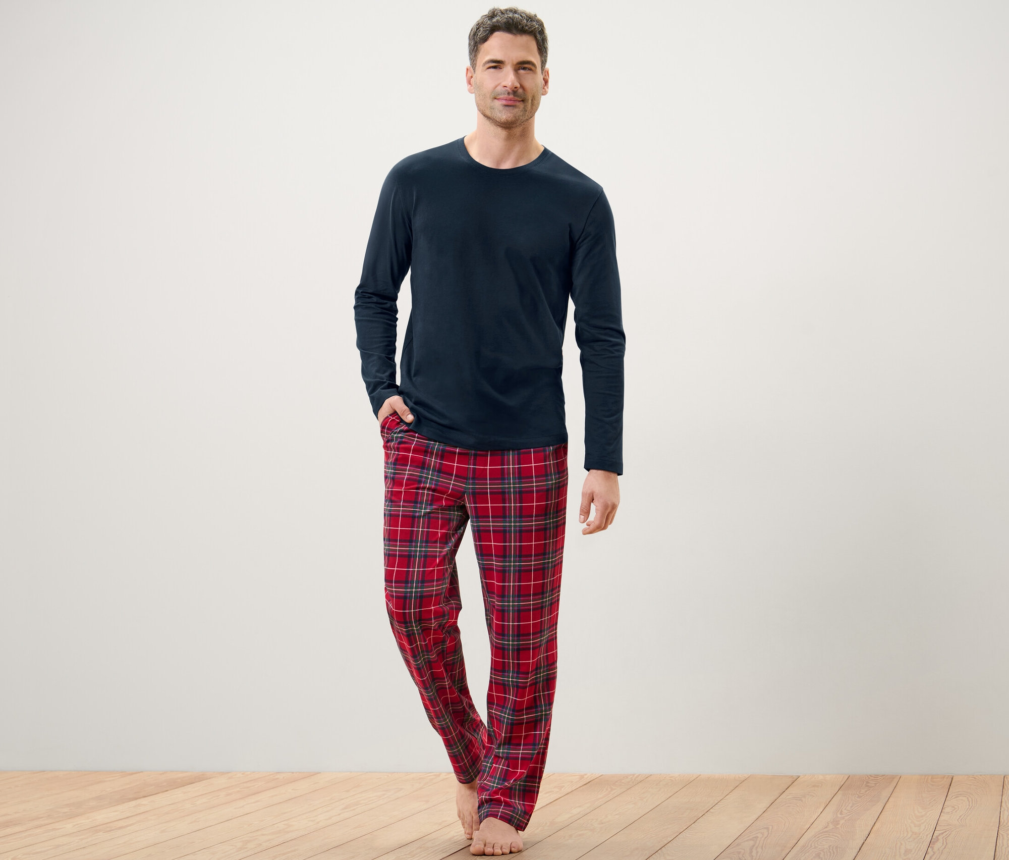 Férfi pózol kék pizsamában kockás nadrággal.