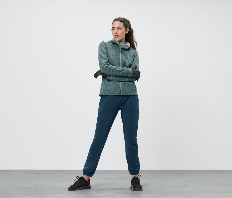 Nő visel melírozott menta kötött polárfelsőt, menta női termodzsekit és sötétkék női funkcionális termonadrágot.