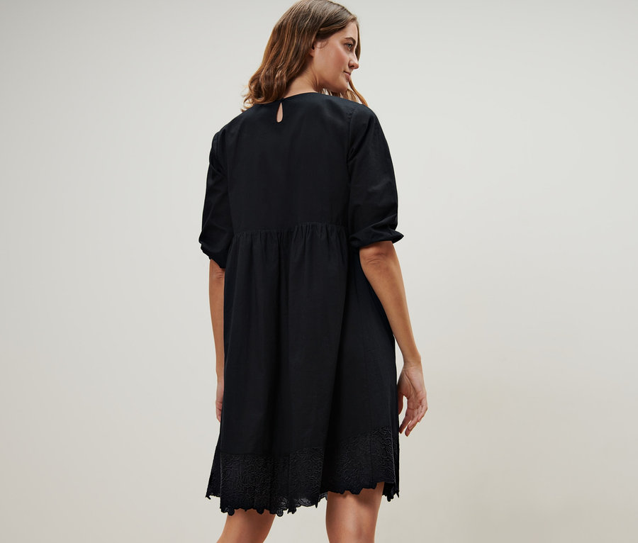 Hátulról látható nő fekete, hímzett szövött ruhában.