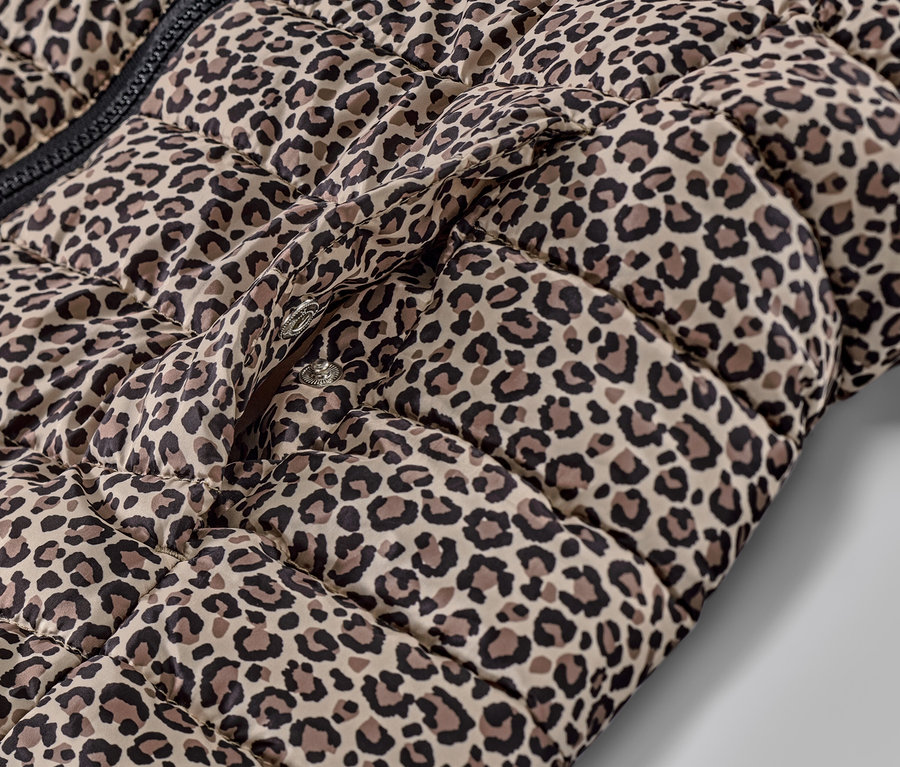 Egy nyomott mintás, kapucnis steppelt mellény részlete, patentos zárással.