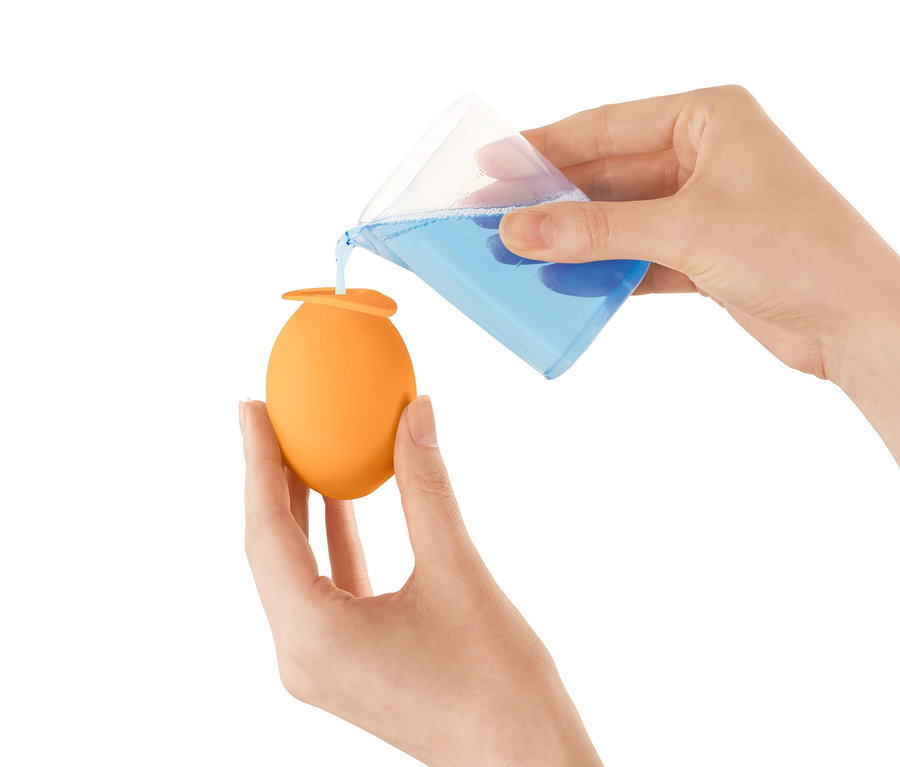 Nő folyadékot önt egy mérőpohárból egy narancssárga vízkőmentesítő fej, csapra termékbe.