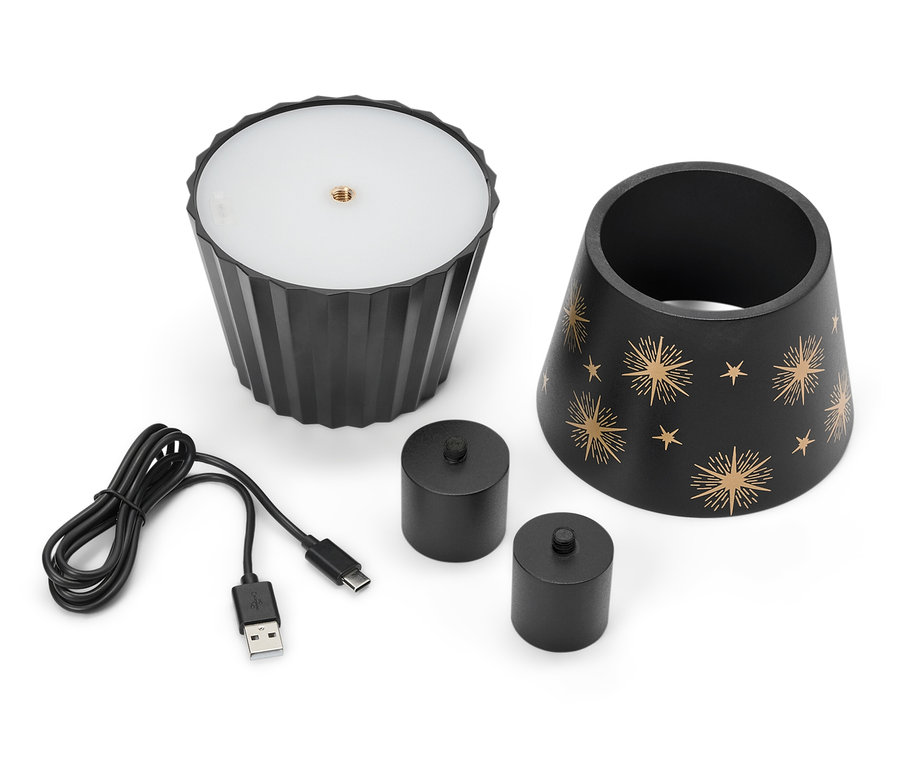 Egy fekete lámpa csillagokkal, két fekete gyertya és egy USB-kábel fekszik egy fehér háttéren.