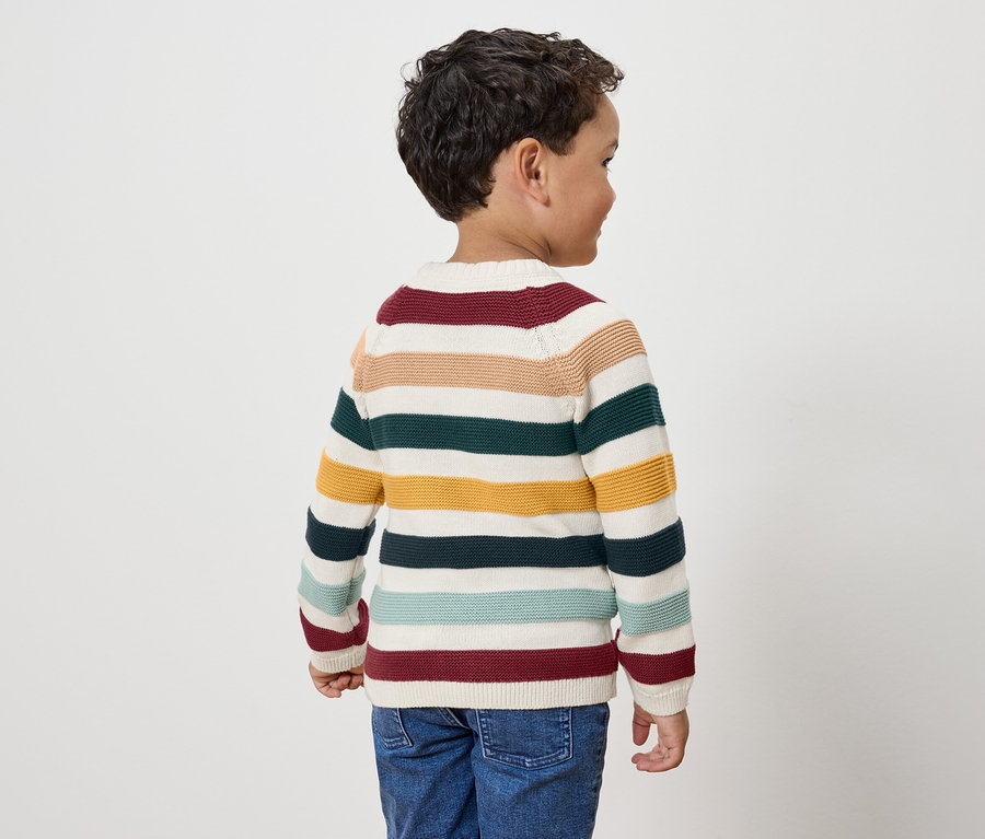 Fiú csíkos pulóverben, háttal a kamerának.