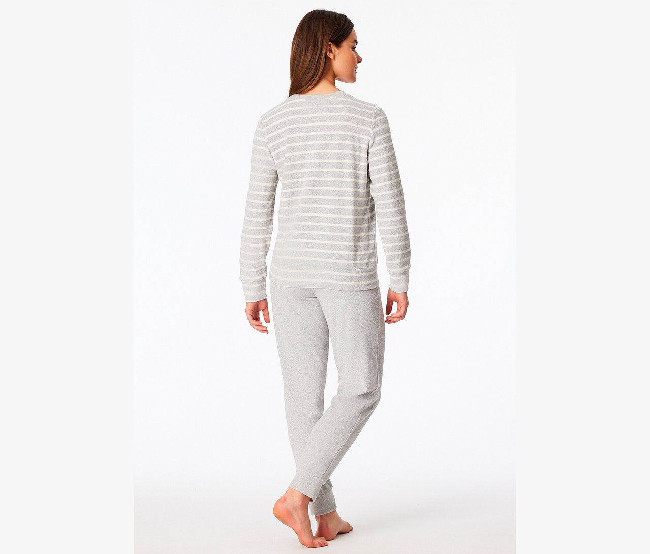 Egy nő áll háttal, szürke, csíkos, hosszú ujjú felsőt és szürke jogging alsót visel.