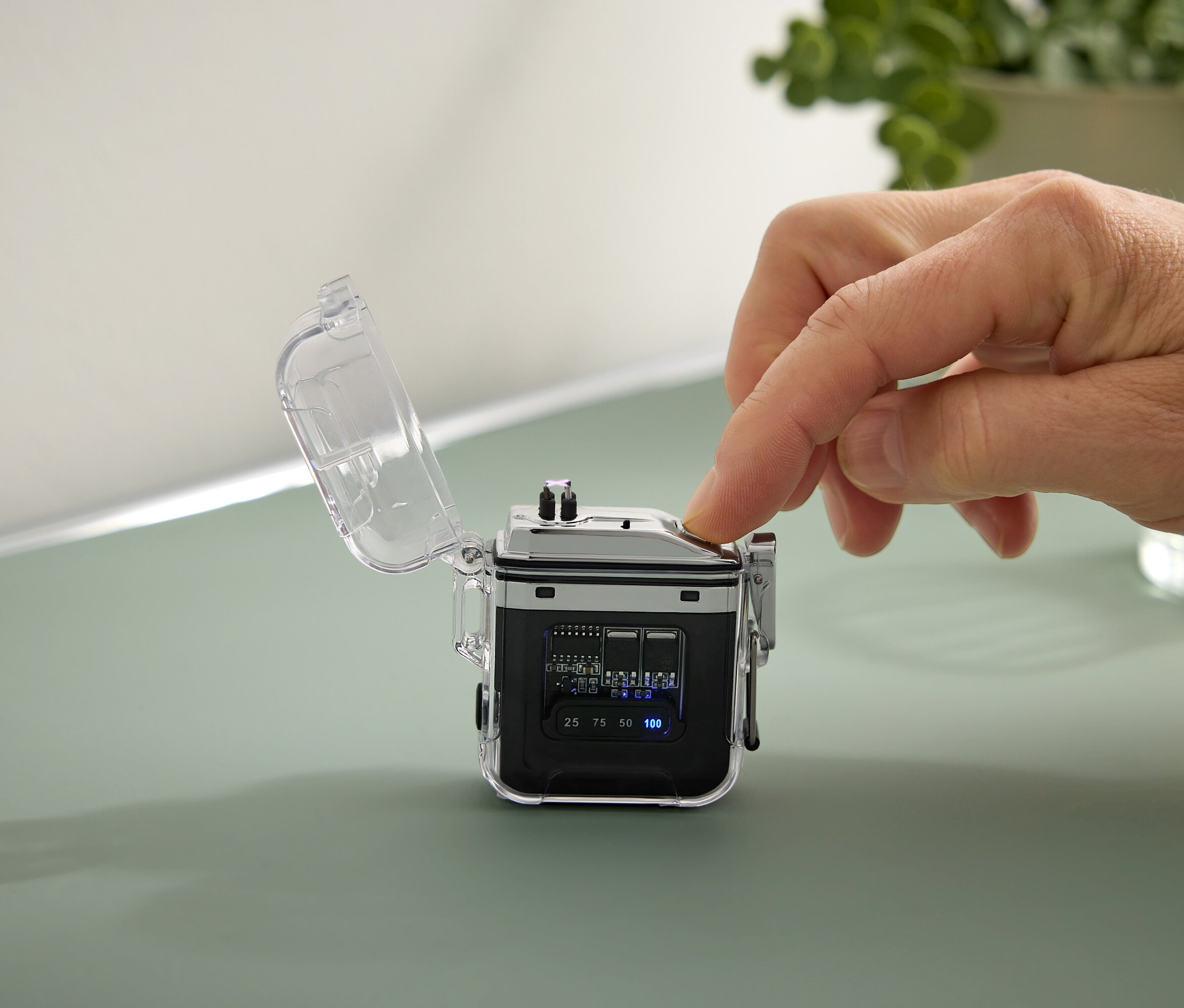 Egy kéz megnyom egy gombot egy kis fekete eszközön, átlátszó tokkal.