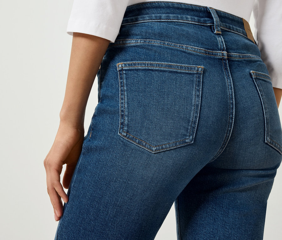 Kék farmernadrág hátsó részének részlete egy alakon.