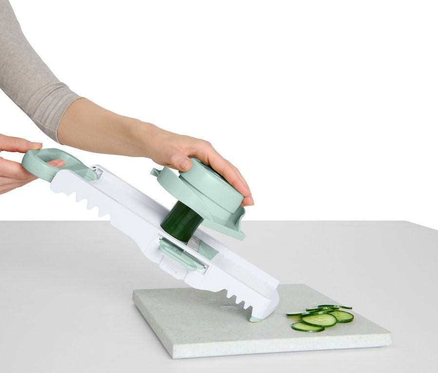 Egy nő uborkát szeletel egy zöldségszeletelővel, fogantyúval és forgó tartozékkal.