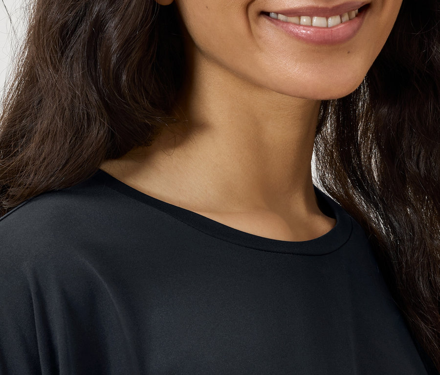 Egy nő arcának részlete sötét, hullámos hajjal és fekete pólóval.