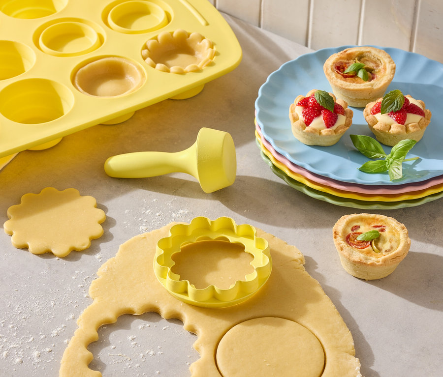 Sárga piteforma kiszúrókkal és kész piték színes tányérokon.