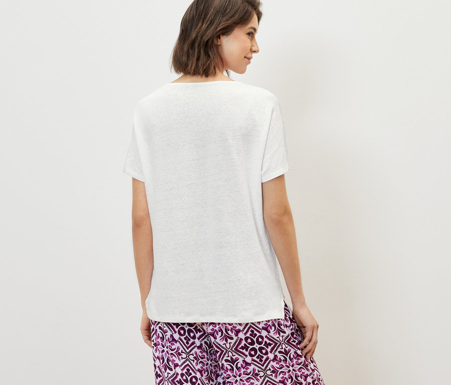 Hátulról látható nő fehér len-keverék pólót és mintás nadrágot visel.