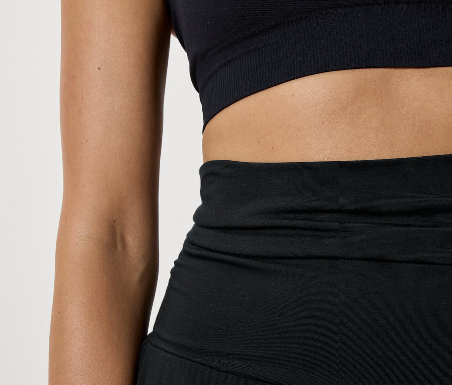 Női fekete sportmelltartó és leggings részlete.