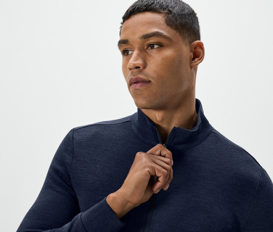 Férfi kék színű, cipzáras pulóvert nyit ki.