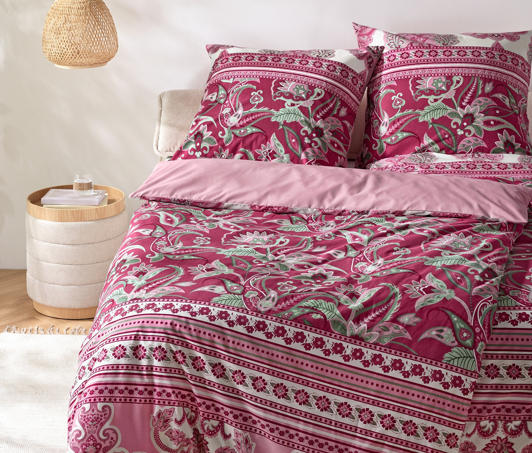 Egy paisley ágynemű szett egy ágyon éjjeliszekrénnyel és lámpával.