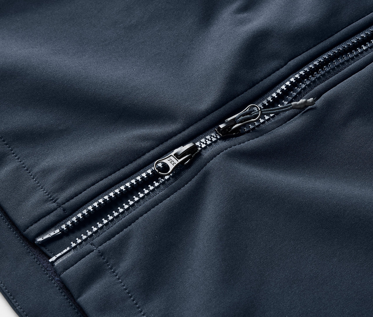 Egy tengerészkék softshell kabát részlete ezüst cipzárral.