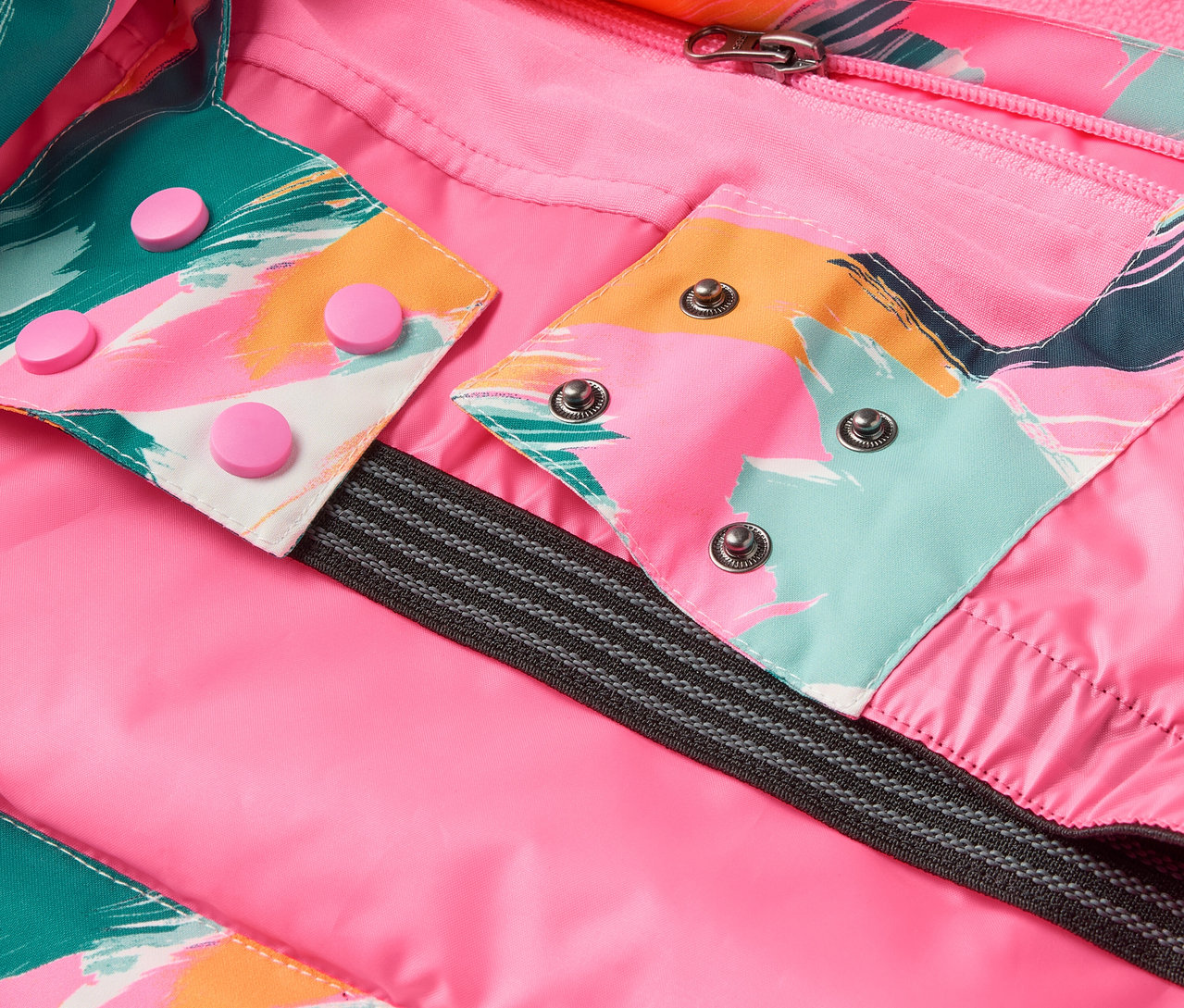 Egy kabát részlete rózsaszín béléssel, színes mintákkal és patentokkal.