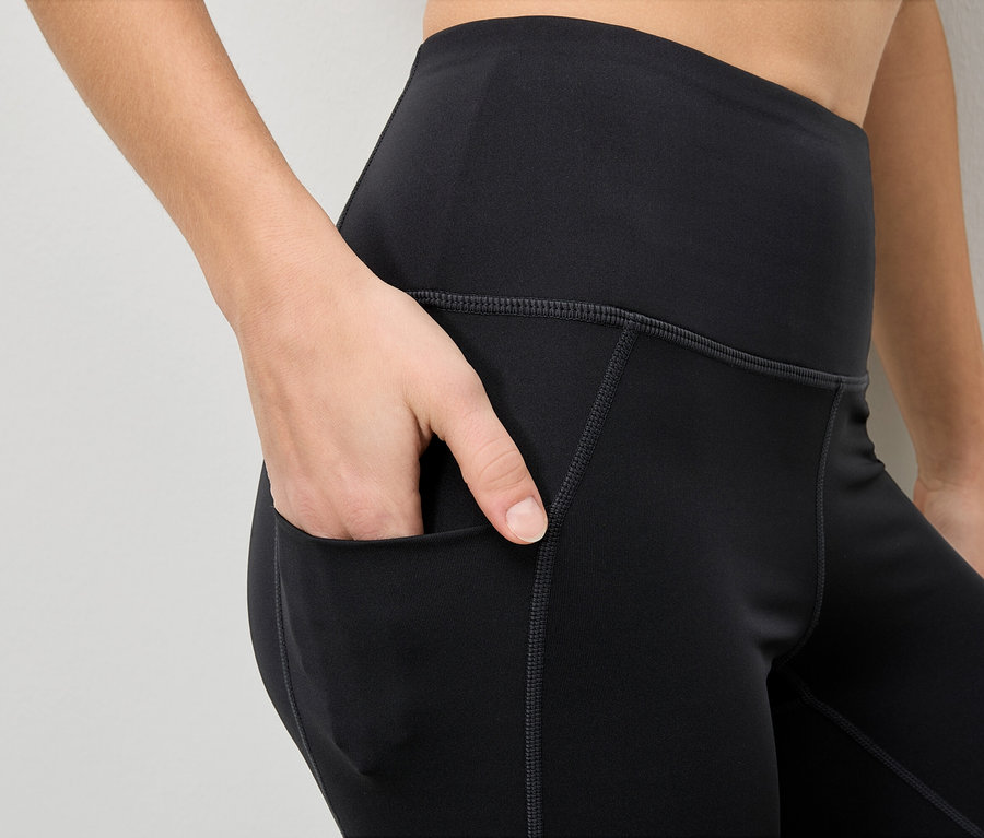 Nő a kezét a fekete leggings zsebébe teszi.