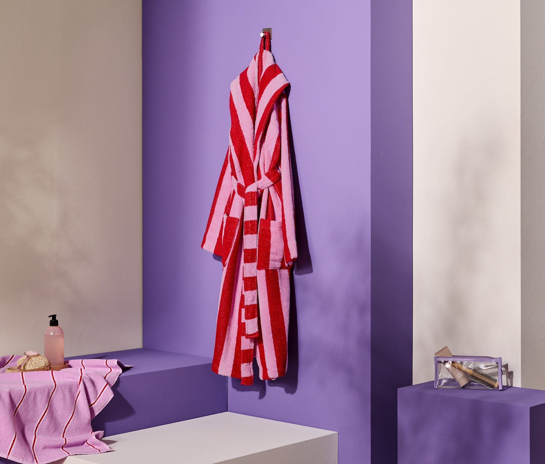 Csíkos köntös lóg a kampón törölköző, szappan és kozmetikai táska mellett.