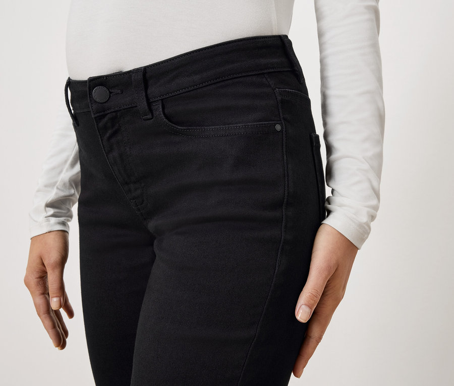 Egy fekete farmernadrágot és hosszú ujjú fehér felsőt viselő személy közeli képe.