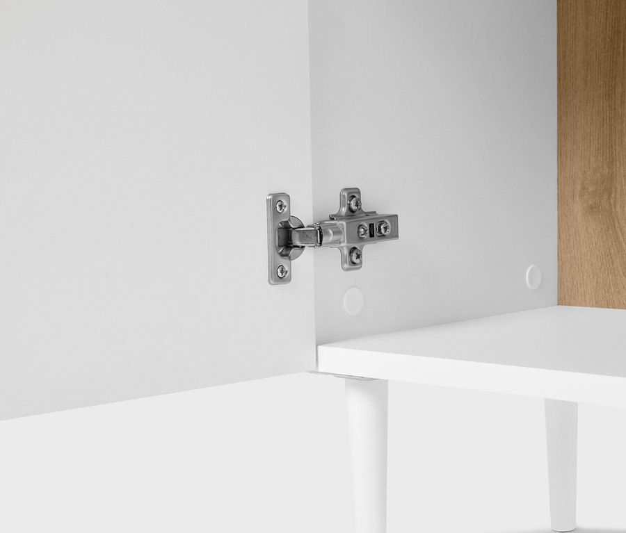 Egy szekrény közeli képe ezüst zsanérral a fehér ajtón.