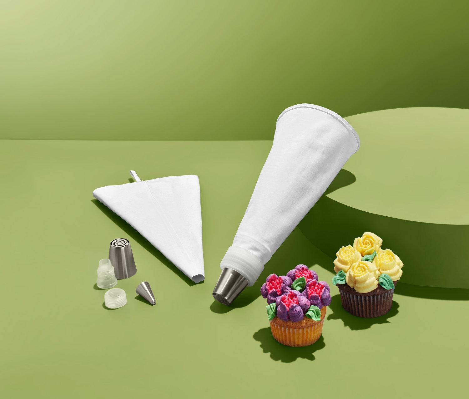 Kinyomócső készlet két díszített cupcake-kel zöld háttérrel.