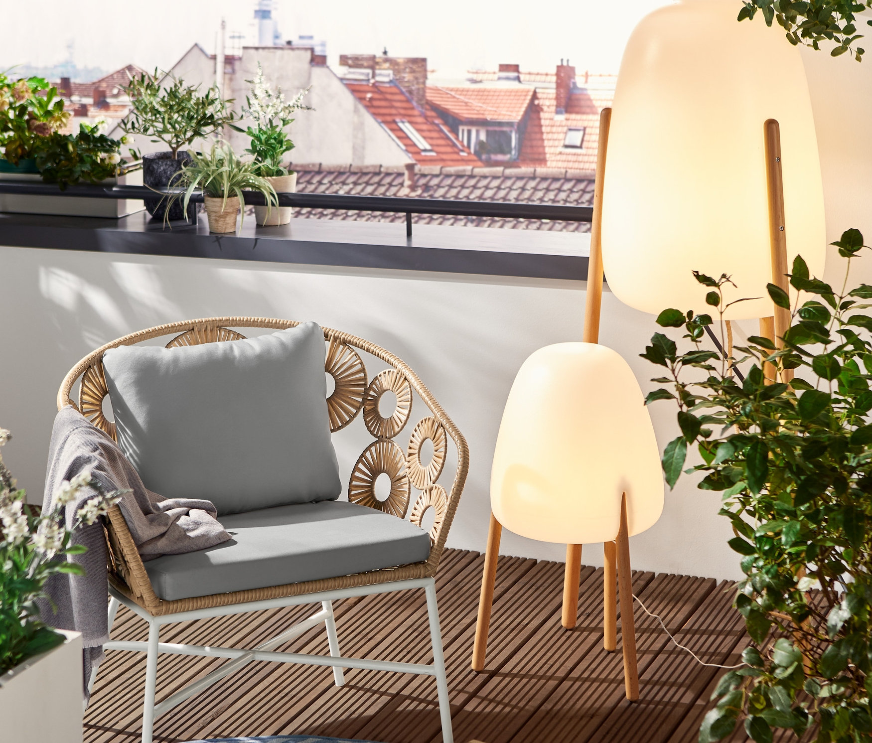 Egy teraszon egy virágmintás lounge szék és egy kerek kültéri szőnyeg látható. A tálcán egy pohár, egy kancsó és egy tál áfonya van.