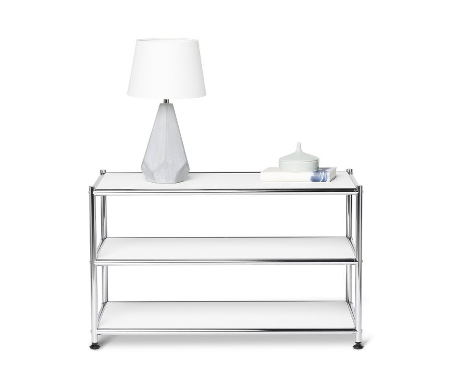 A fehér fém dohányzóasztal felső polcán egy lámpa és dekorációk állnak.