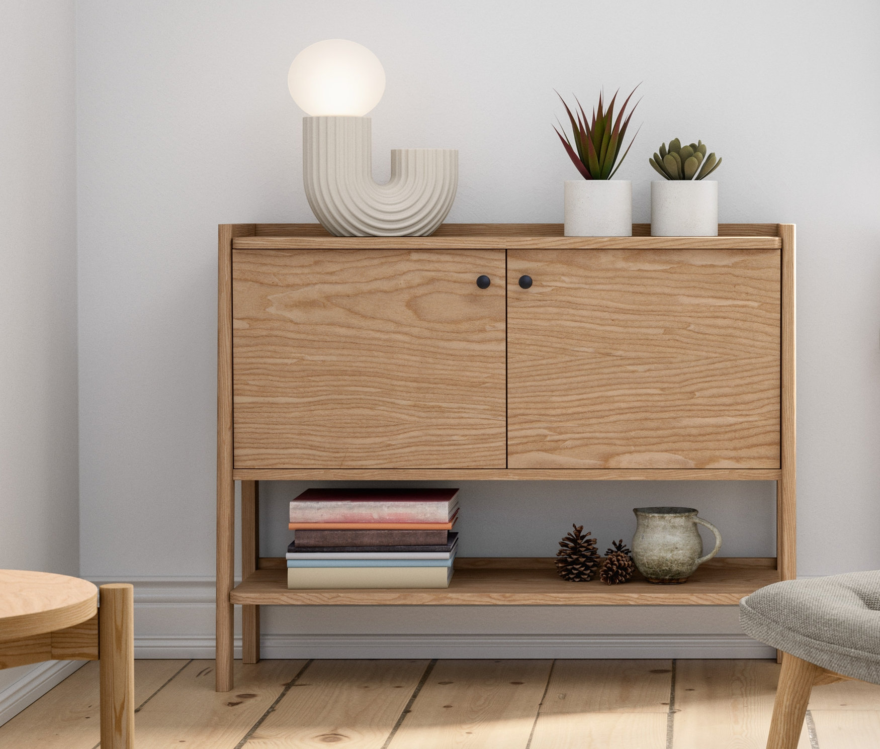 Belső tér fa komóddal, LED-es asztali dizájnlámpával, kárpitozott fotellel, lábtartóval, cserepes növényekkel és dekorációkkal.