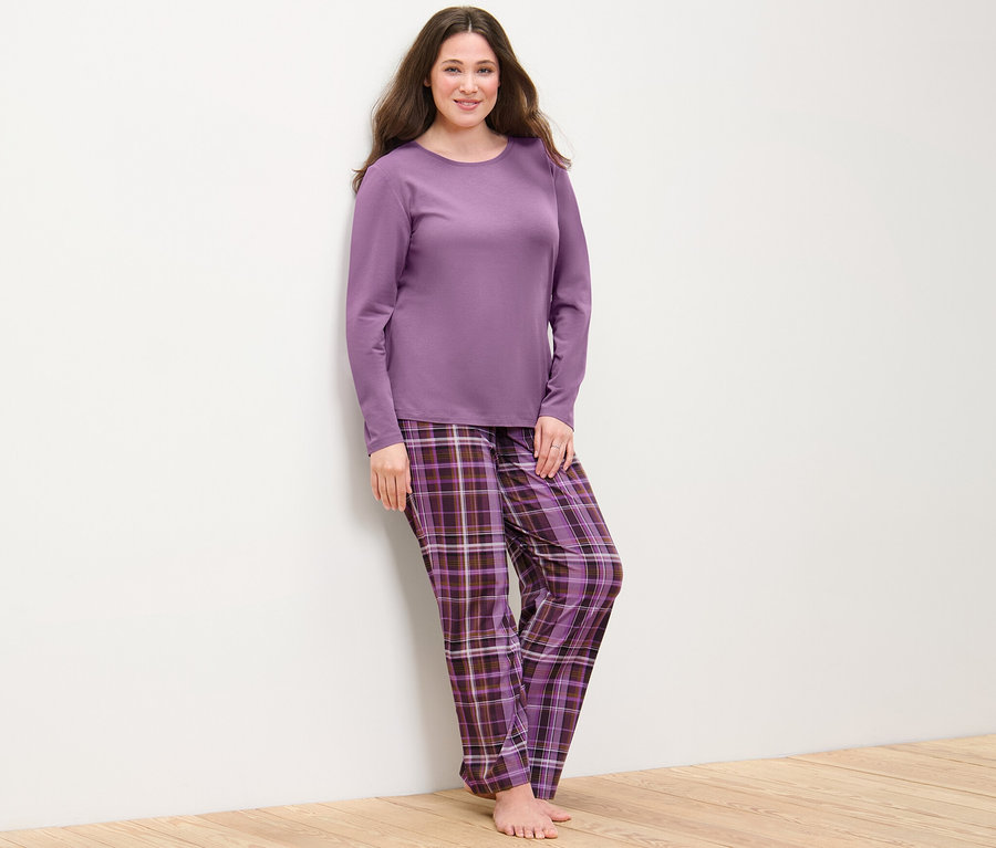 Nő pózol egy kockás lila női pizsamában.
