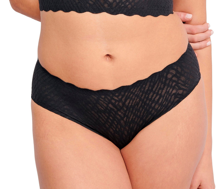 Fekete sloggi ZERO Feel Bliss hipszter alsót és hozzá illő bralette-et viselő személy, kezeit a háta mögött összefonva.