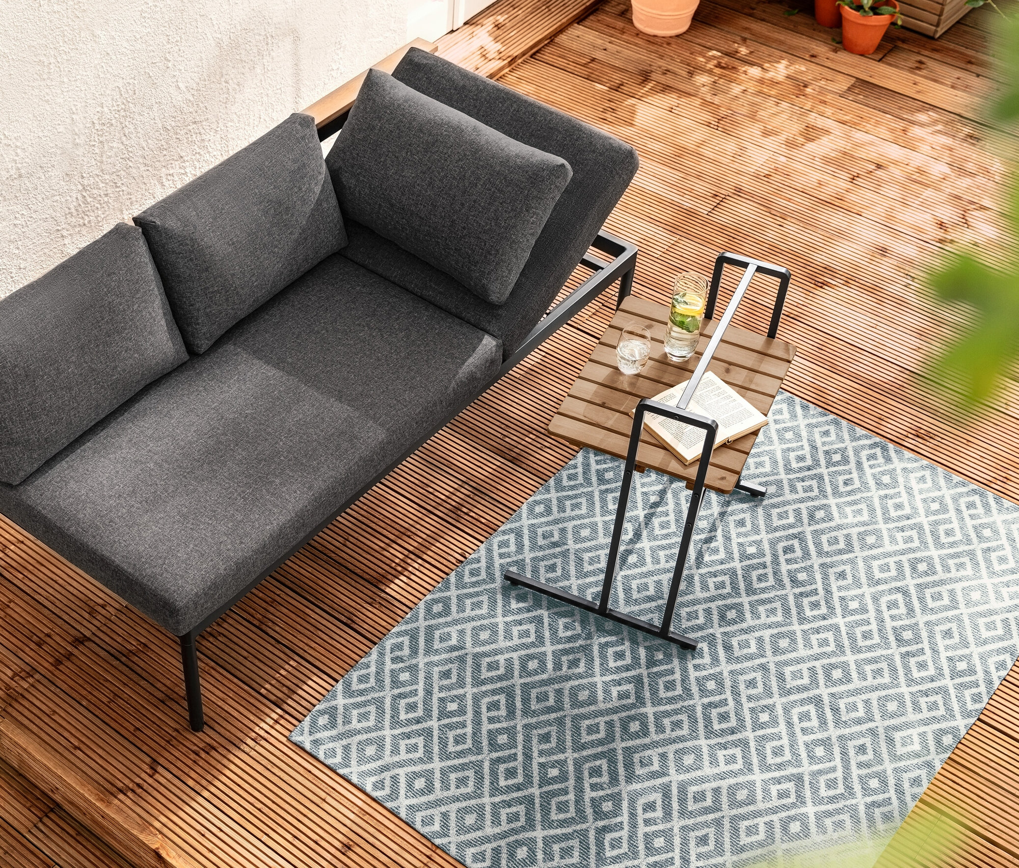 Felülnézet egy Elin 2 az 1-ben étkezőpad-ággyal egy nagy asztallappal rendelkező C-asztal mellett egy fa teraszon.