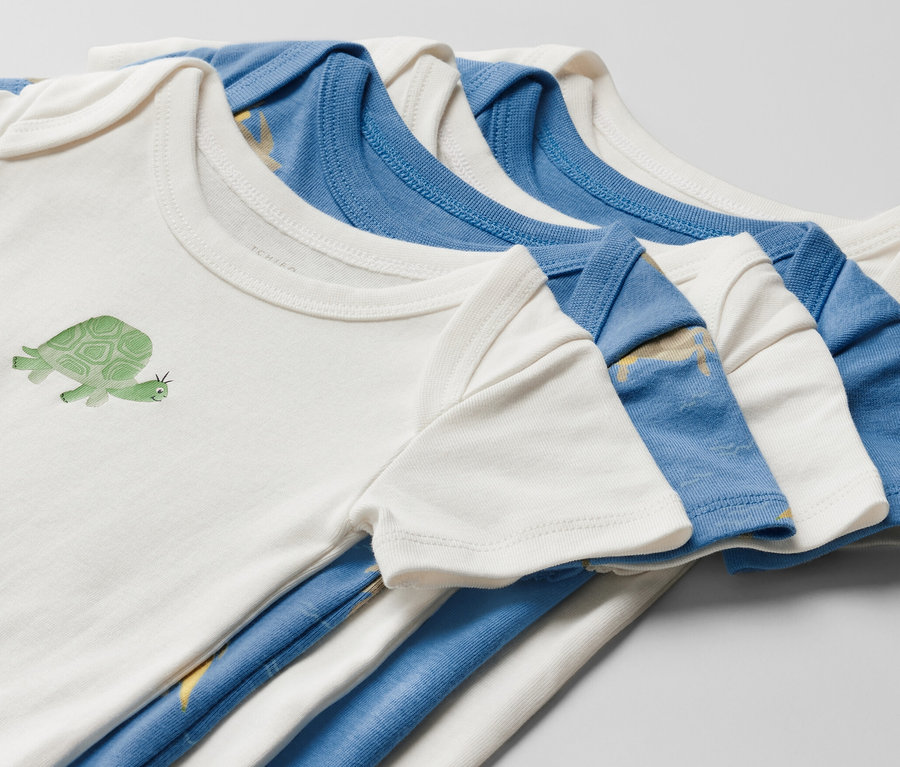 Öt rövid ujjú baba body közelképe. Egy fehér body teknős mintával.