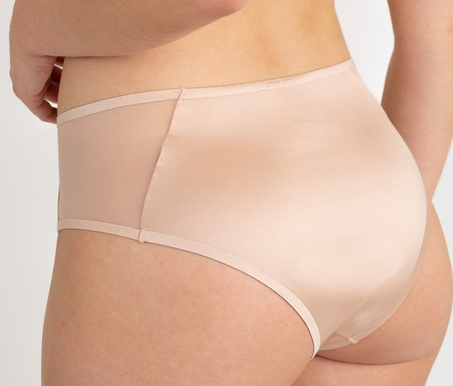 Hátulnézet egy bézs színű, áttetsző betétekkel ellátott bugyit viselő nőről.