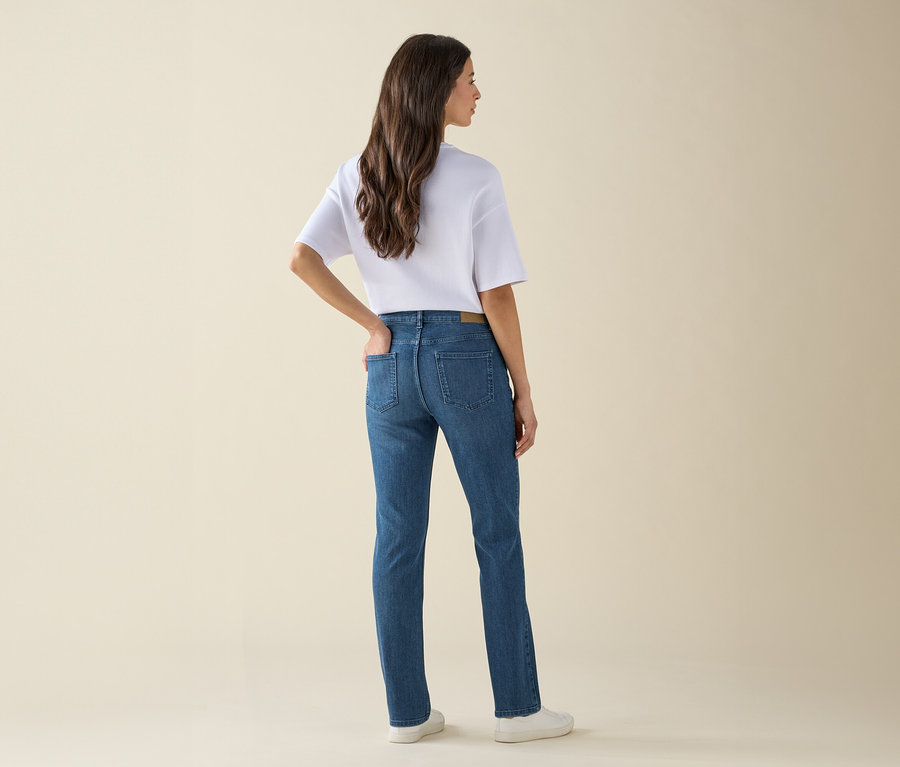 A kamerának háttal álló nő farmert, pólót és tornacipőt visel.