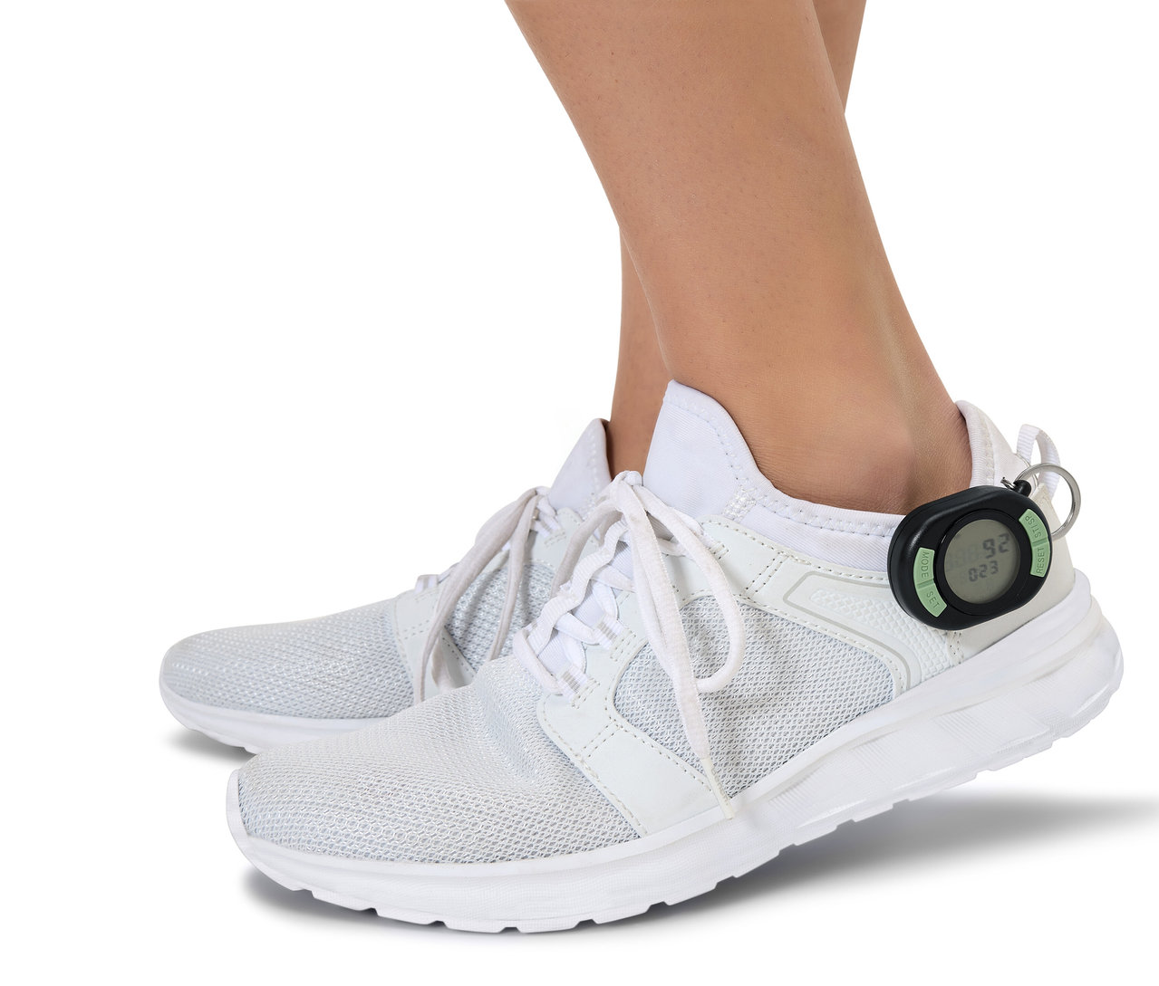 Lábak fehér cipőben, az egyik cipő sarkához fekete lépésszámláló van rögzítve.