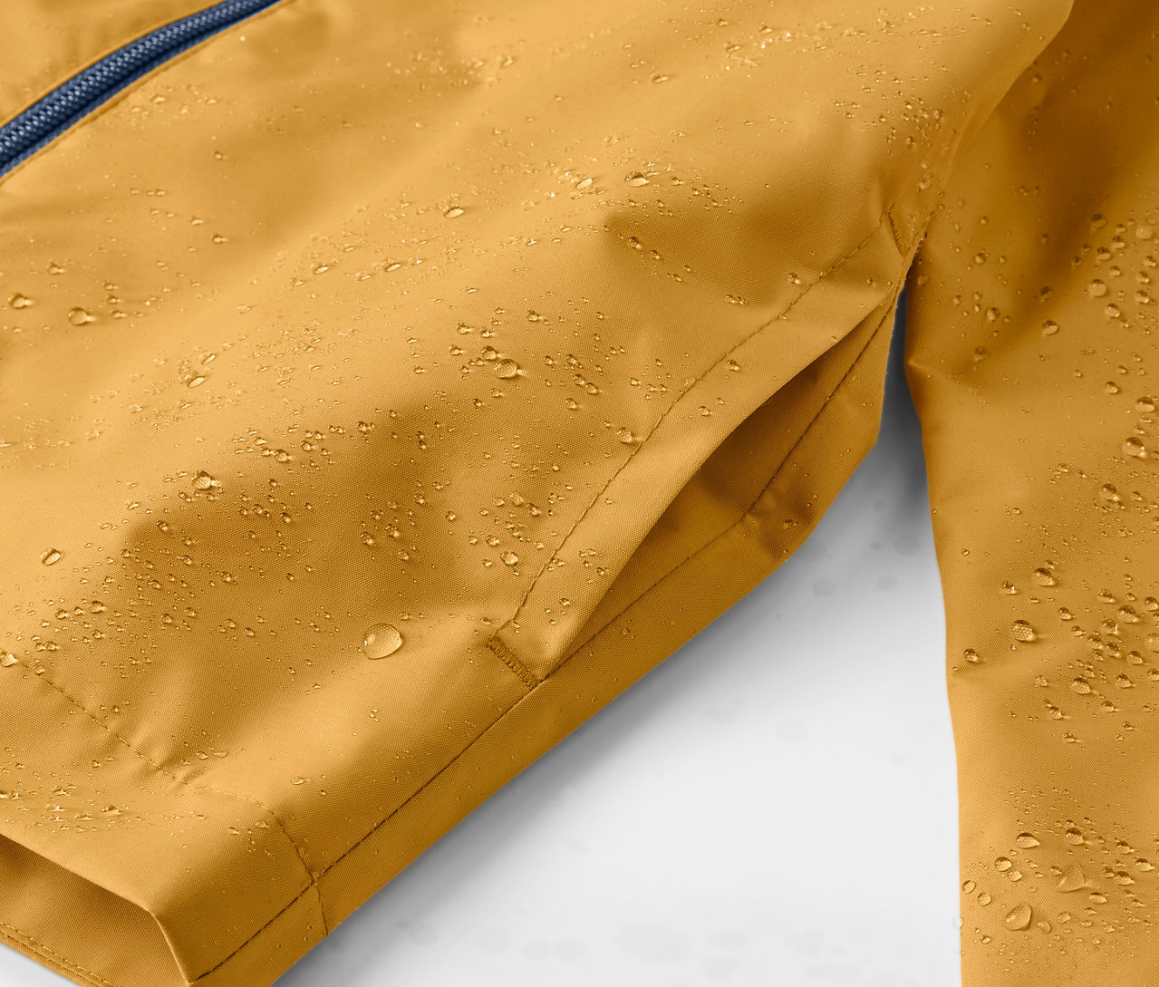 Egy sárga gyerek esőkabát részlete vízcseppekkel.