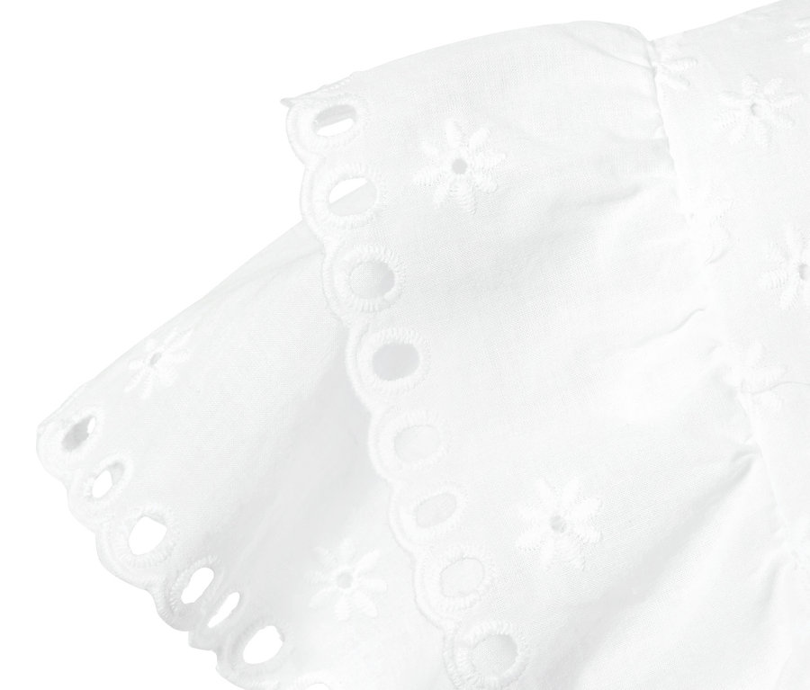 Egy fehér, hímzett női felső részlete.