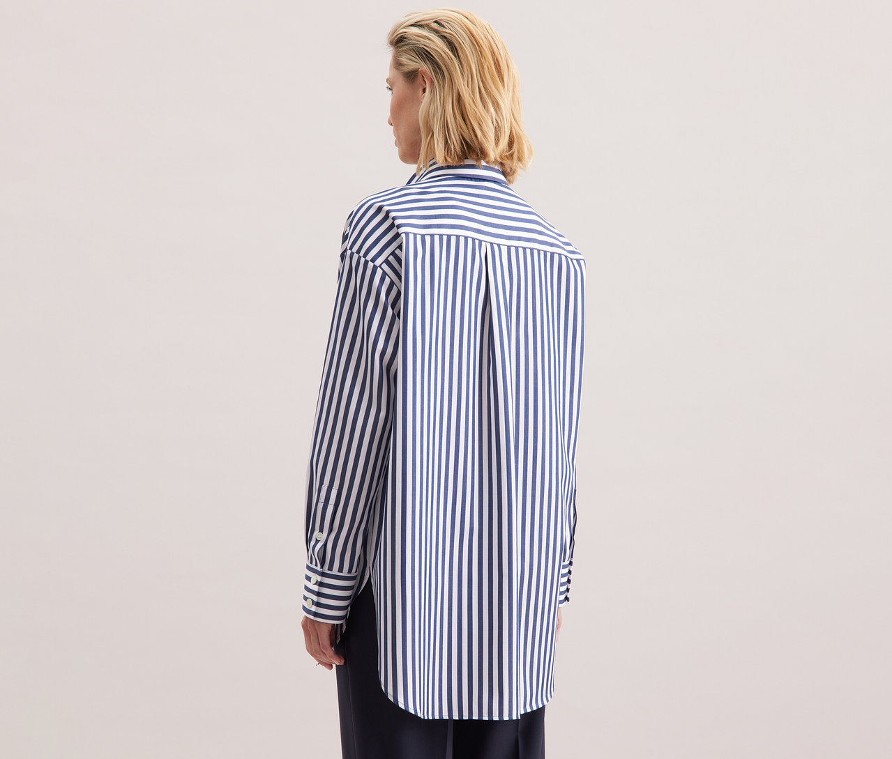 Hátulról egy szőke nő visel egy csíkos Seidensticker túlméretes hosszú blúzt.