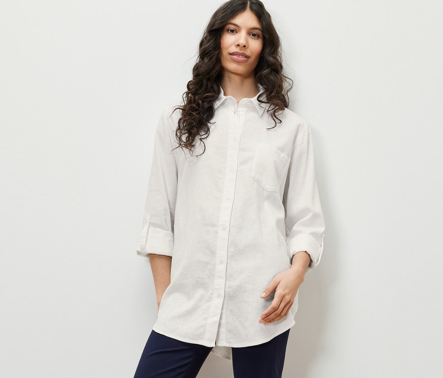 Nő pózol hosszú, lenvászon, fehér blúzban.