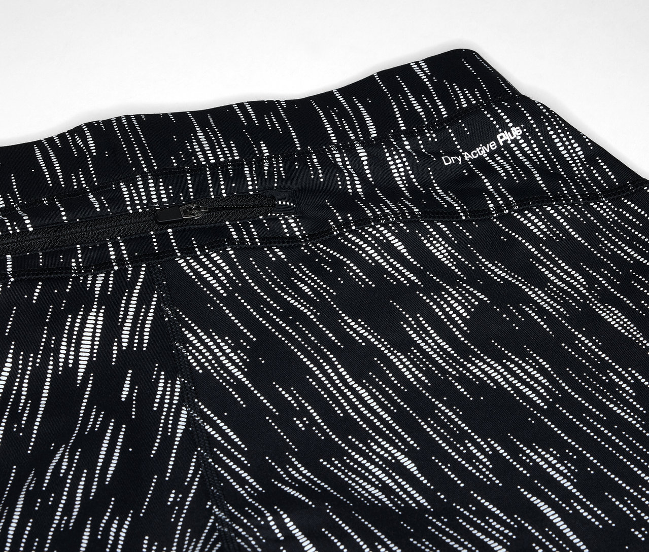 Egy fekete leggings részlete fehér vonal mintával és cipzáras zsebbel.