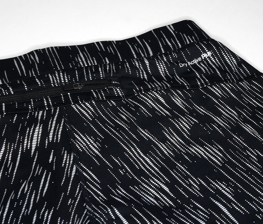 Egy fekete leggings részlete fehér vonal mintával és cipzáras zsebbel.