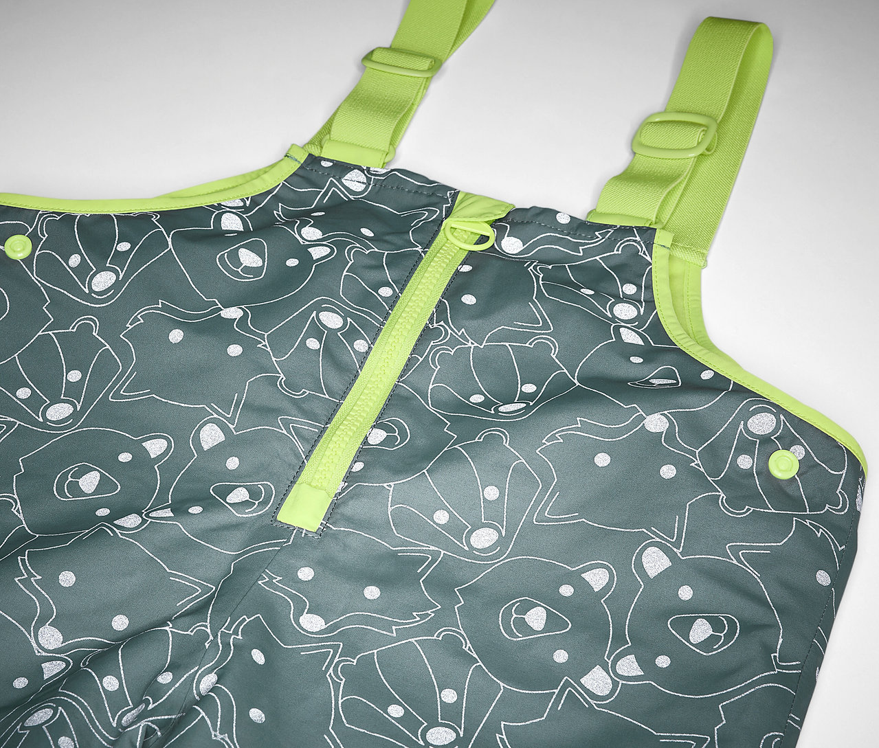 Egy termo esőnadrág részlete fényvisszaverő elemekkel, szürke színben, medve- és rókamintával, sárga pántokkal, gyermekeknek.