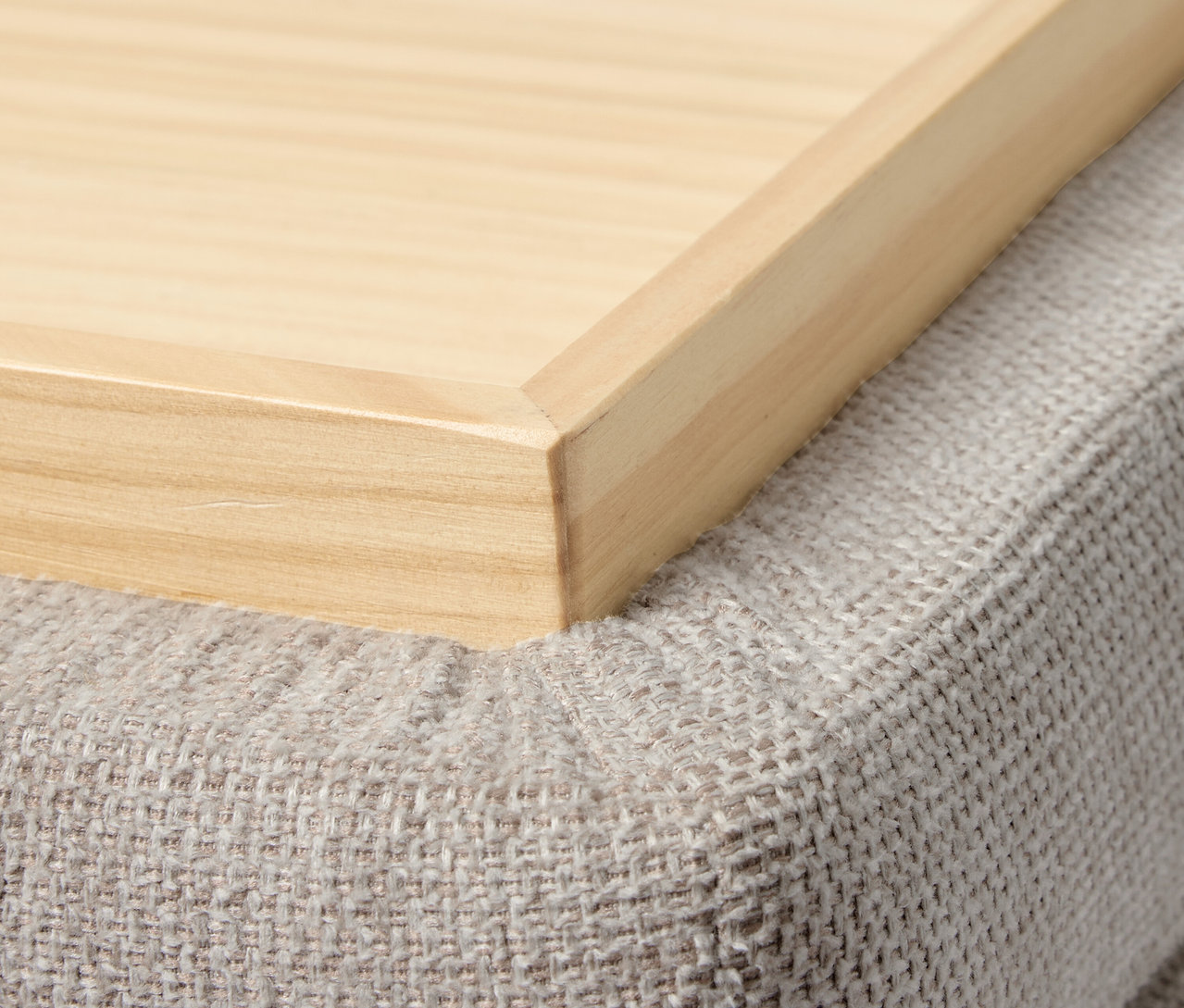 Egy fa tálca részlete egy szürke puffon.