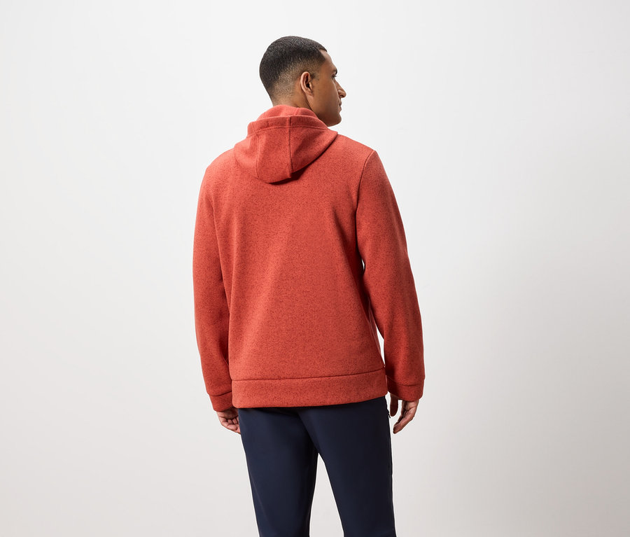 Egy férfi háttal a kamerának narancssárga kapucnis pulóvert és sötétkék nadrágot visel.