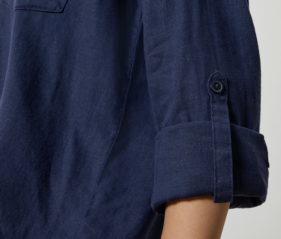 Közeli kép egy sötétkék vászon ingről, felhajtott ujjakkal és gomb részletekkel.