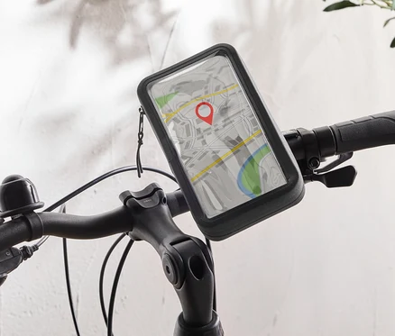 Egy fekete kerékpár, amelynek kormányán egy mobiltelefon-tartó található, amely egy térkép alkalmazást mutat egy piros rajzszöggel.