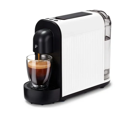 A Cafissimo now white kávéfőző kávéval tölt egy csészét. A gép fehér, fekete díszítéssel és átlátszó víztartállyal rendelkezik.