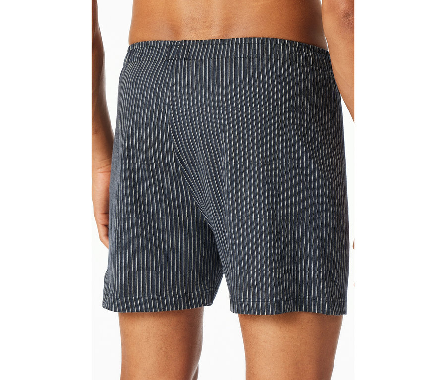 Hátulról látható személy, aki kék SCHIESSER jersey boxeralsót visel vékony fehér csíkokkal.