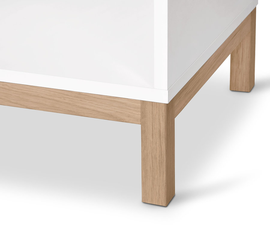 A fehér »Eklund« komód részlete ruhasínnel és világos fa lábakkal.