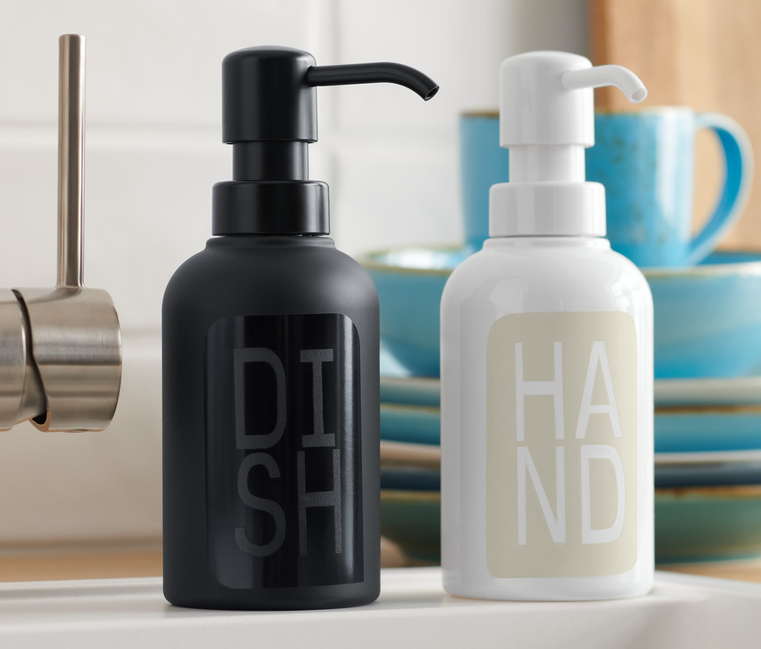 Fekete és fehér 2 szappanadagoló áll a mosogató mellett.